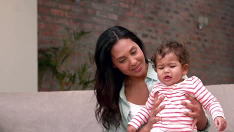 Madre-Joven-En-El-Sofá-Sosteniendo-A-Su-Bebé