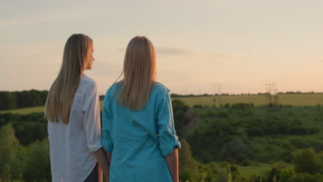 una mujer con su hija adolescente admirando la puesta de sol en un pintoresco valle