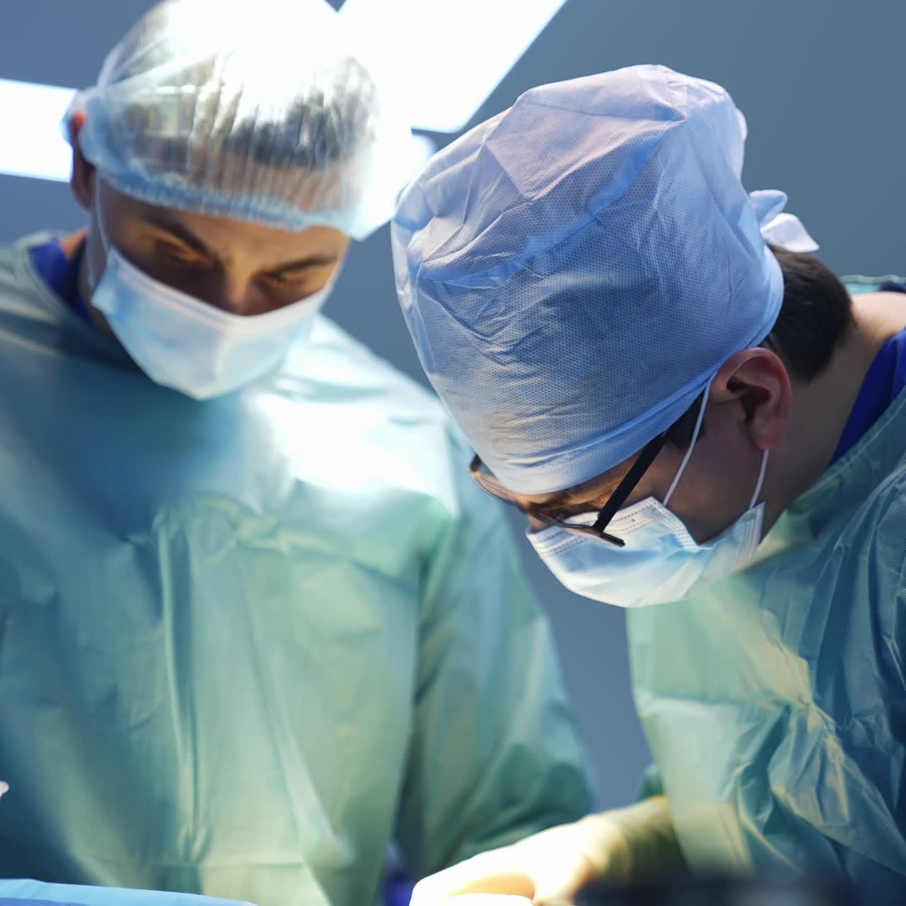 Professional surgeons operate. Portraits of two doctors in blue medical uniform in protective masks perform an operation in clinic