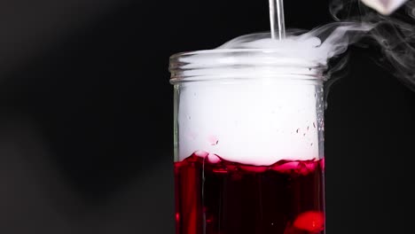 a beaker with red liquid and dry ice creates a smoky, bubbling effect, captured in a dark setting