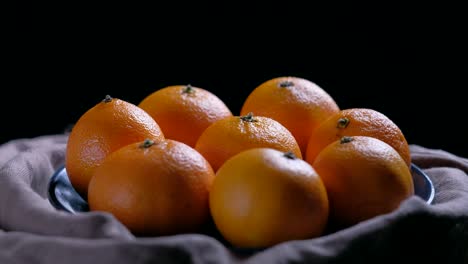 pile of unpeeled round ripe orange mandarin in a plate