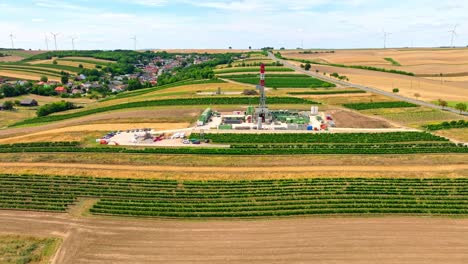 oil and gas land drilling rig in the middle of agricultural fields in austria - aerial panoramic