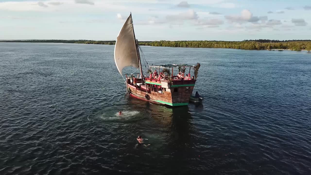 Aerial of people jumping off sailing boat. Summer vacation in Watamu, Kenya