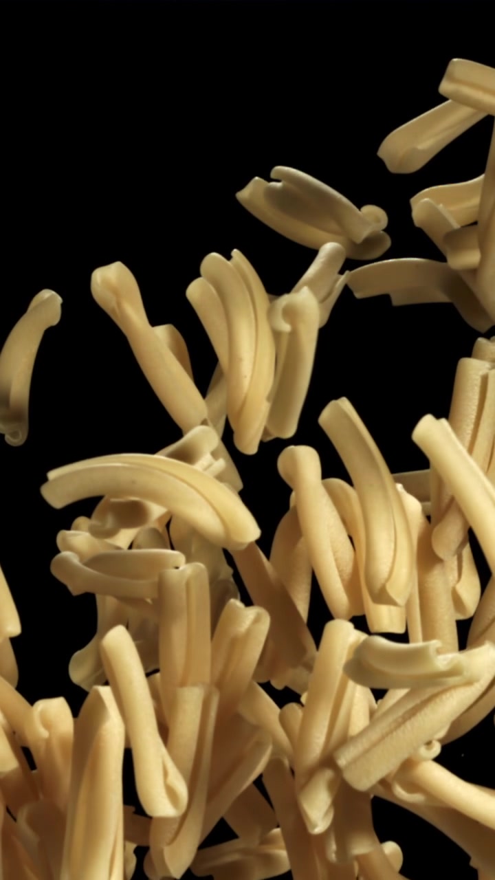 Uncooked Pasta Falling in Slow Motion Against a Black Background