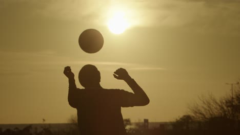 a person practices ball skills in the sunset, with a glowing sky in slow motion