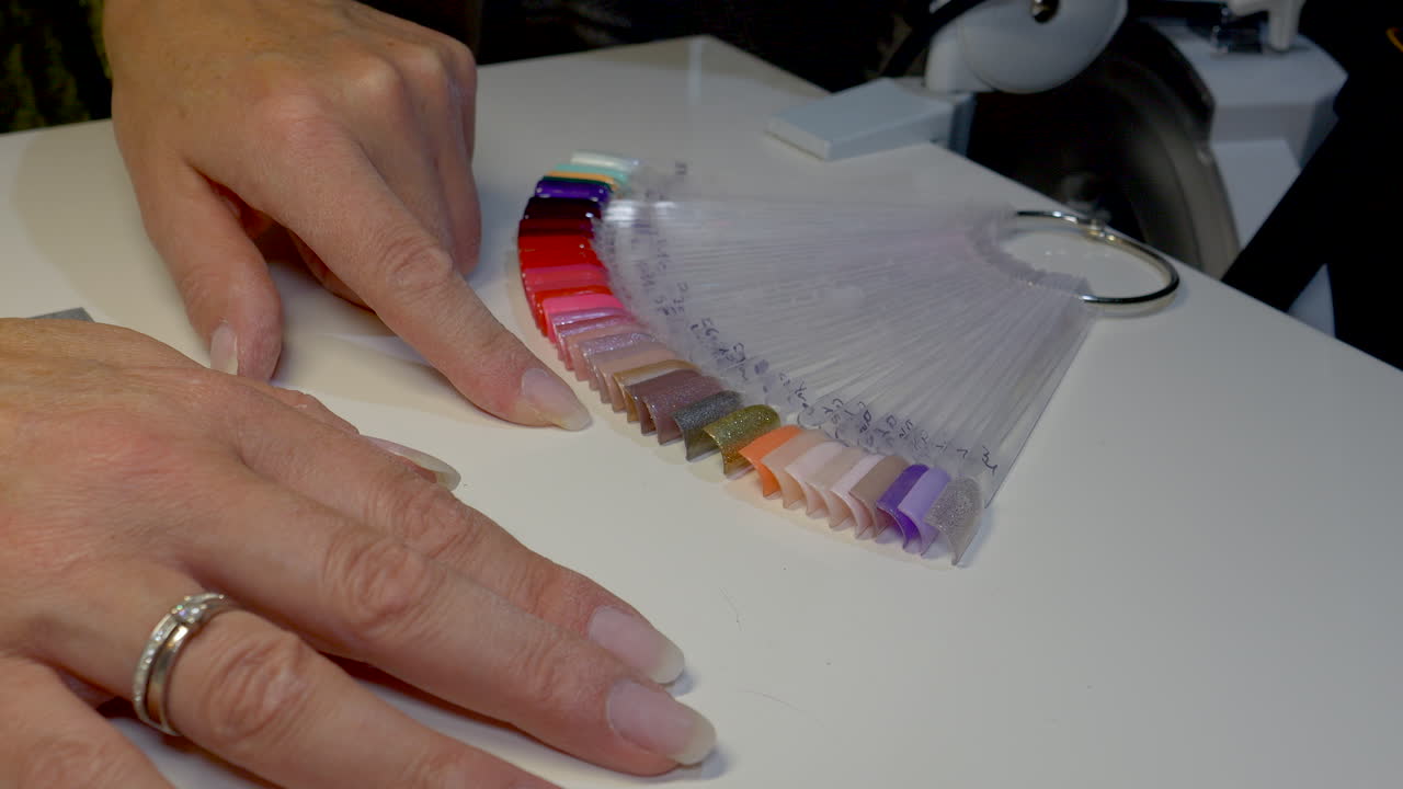 dedo de una persona femenina comprobando los colores de la paleta de colores en el estudio de uñas, de cerca