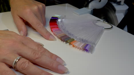 Finger-of-female-person-checking-colors-of-color-palette-in-nail-studio,close-up