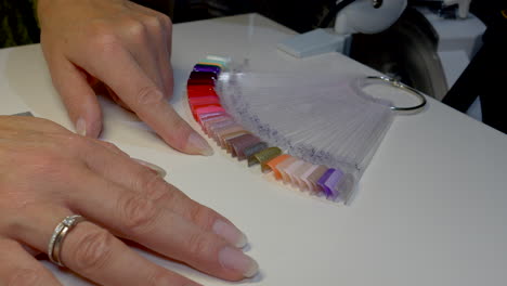 finger of female person checking colors of color palette in nail studio,close up