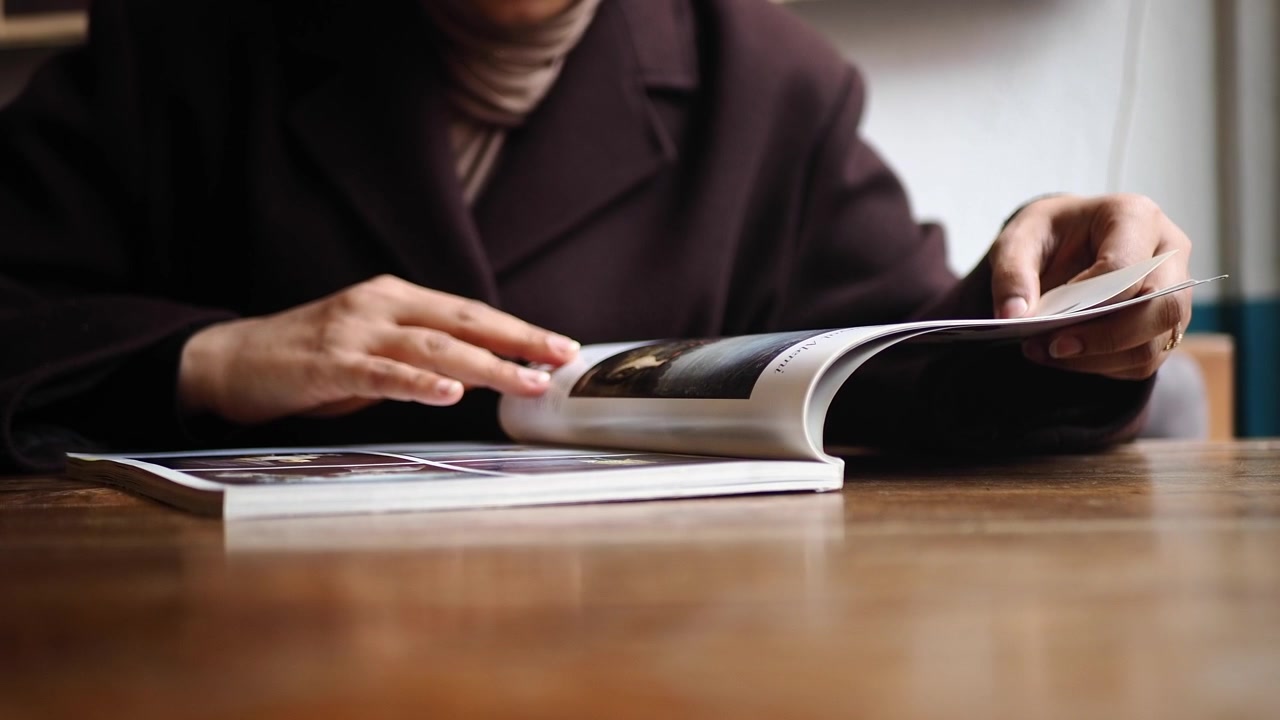Pessoa Lendo uma Revista em uma Mesa de Madeira