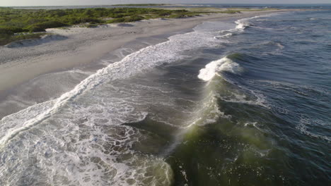 Un-Dron-Panorámico-Disparó-Sobre-Las-Olas-Y-El-Oleaje-Chocando-Contra-La-Playa,-A-Solo-Unos-Metros-Sobre-El-Agua