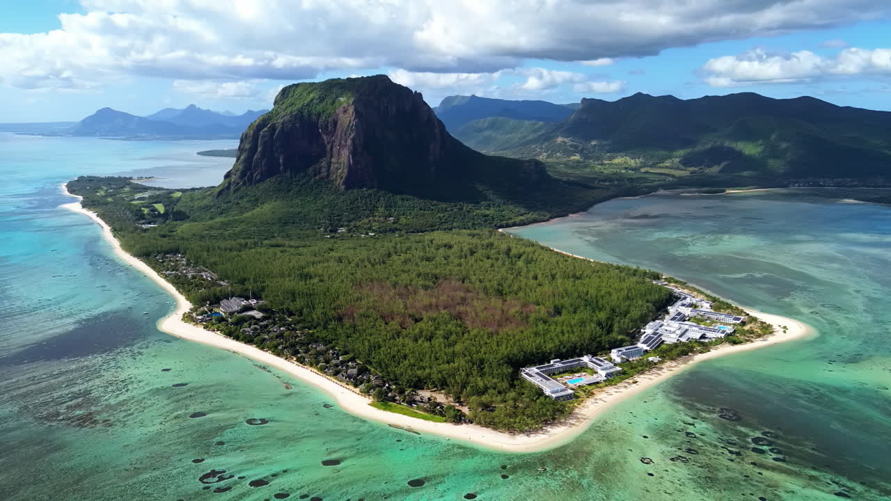 Vista aérea de drone da península de Le Morne Brabant nas Maurícias, mostrando recifes de coral, águas azul-turquesa da lagoa e a icónica montanha que se eleva acima da costa tropical.