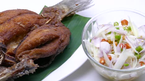 close-up footage of deep fried sea bass served with spicy sour mango salad