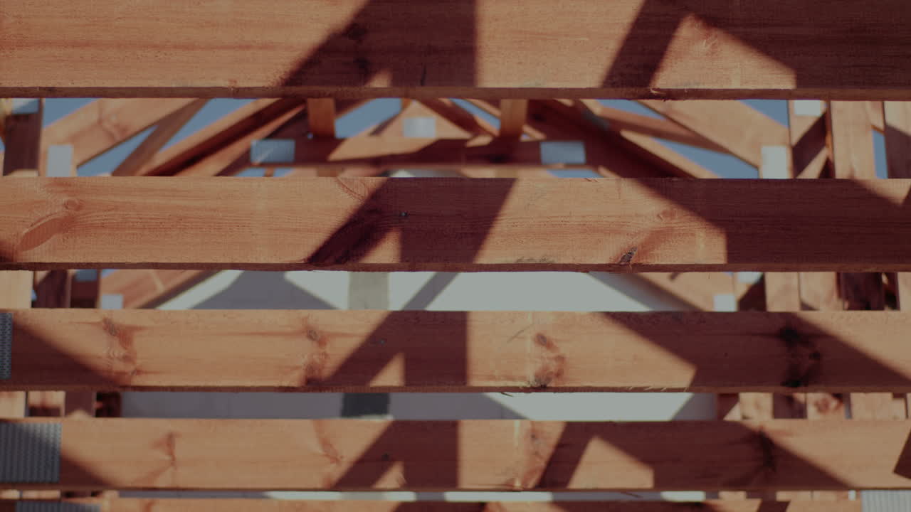 Tilt up shot of brown wooden roof beams at incomplete construction site