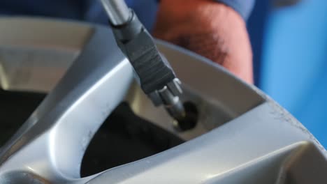 primer plano de manos masculinas instalando un nuevo pezón en el disco de la rueda de un coche