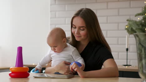 mother and baby are looking to play tablet computer on the couch at home