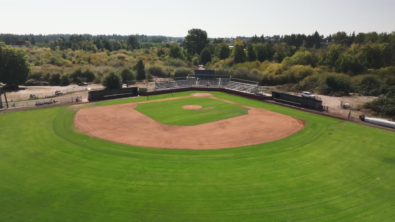 Campo da baseball recentemente rinnovato con erba tagliata di fresco, campo interno in terra battuta e tribune di metallo. Ripresa aerea orbitante con drone