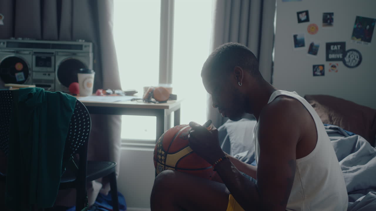 Black Basketball Player Writing a Signature on a Ball at Home