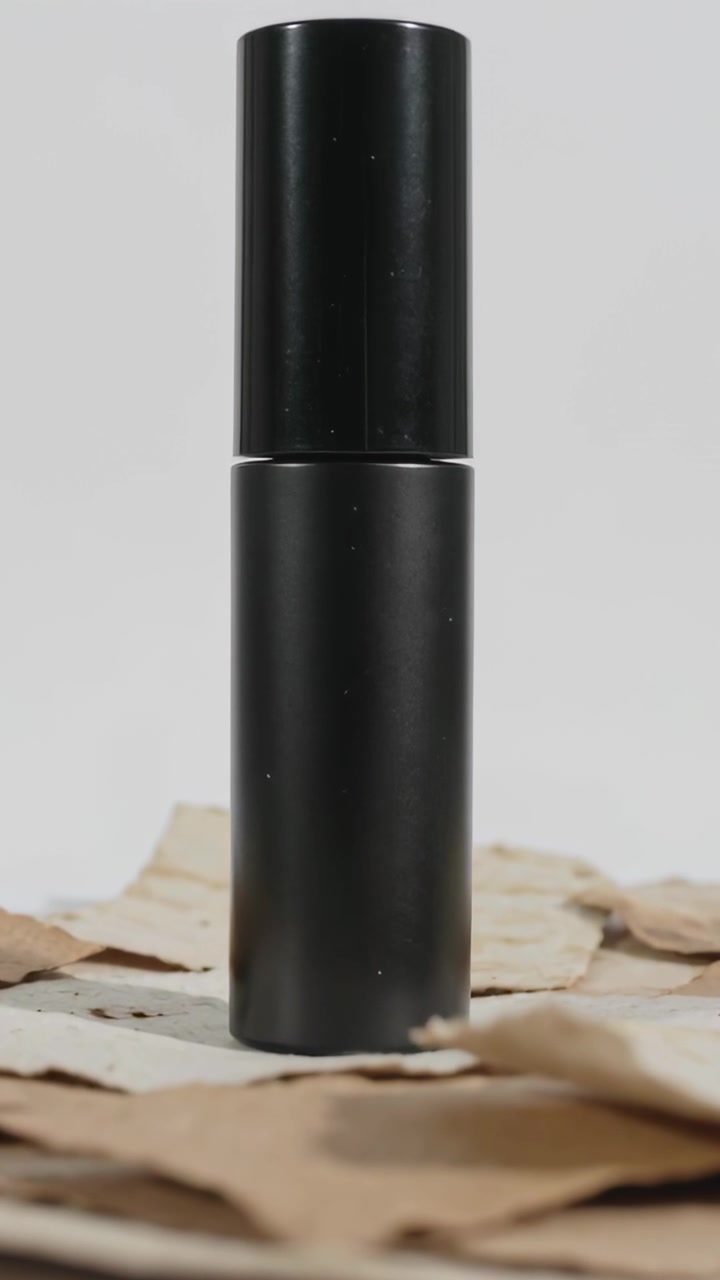 Vertical video: Showing black tube while camera jittering on tabletop for display, torn cardboard