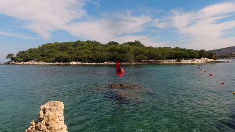 impresionante paisaje de la bandera albanesa ondeando frente a la isla ksamil en un día claro