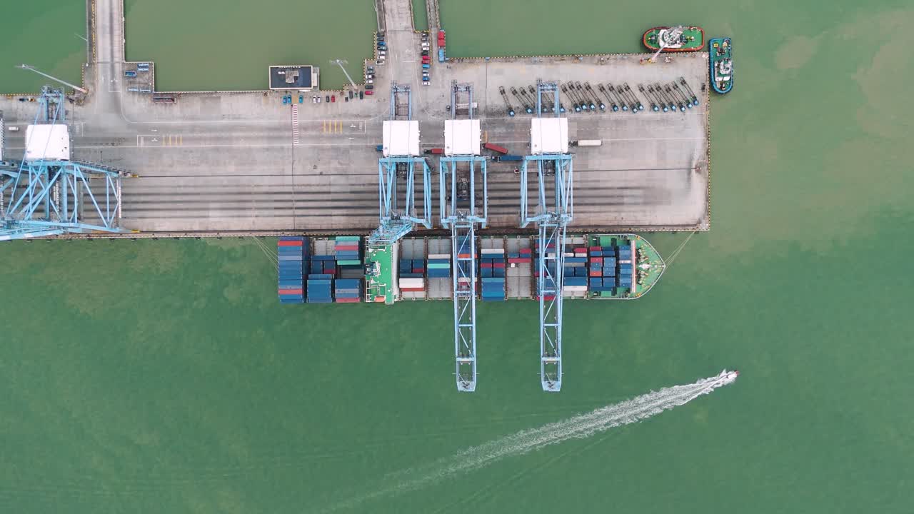 Bird's eye view drone shot of containers loading on a cargo ship at Klang Port during the day in the state of Selangor, Malaysia