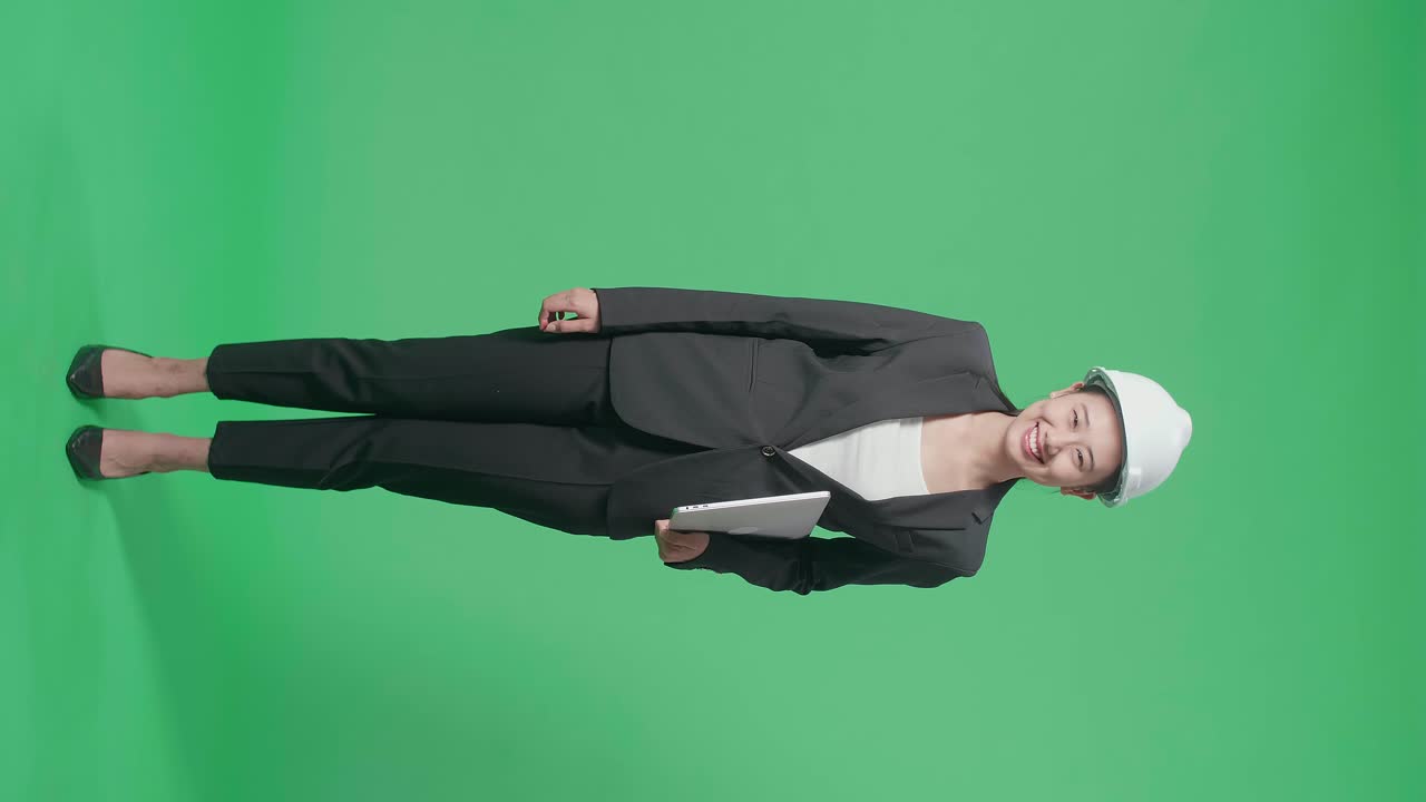 Full Body Of Smiling Asian Female Engineer With Safety Helmet Holding A Laptop In The Green Screen Studio