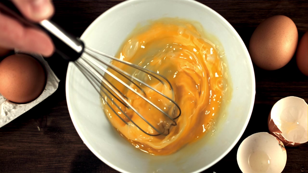 Visping av rå egg i en hvit bolle, sett ovenfra i sakte film