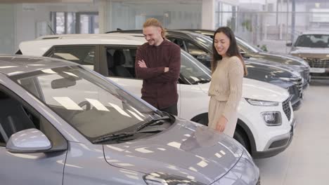 beautiful young couple at car showroom choosing a new car to buy.