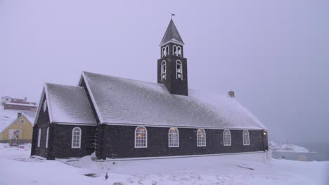 slow motion video of a snow-covered church on the coast in a blizzard in ilulissat, greenland