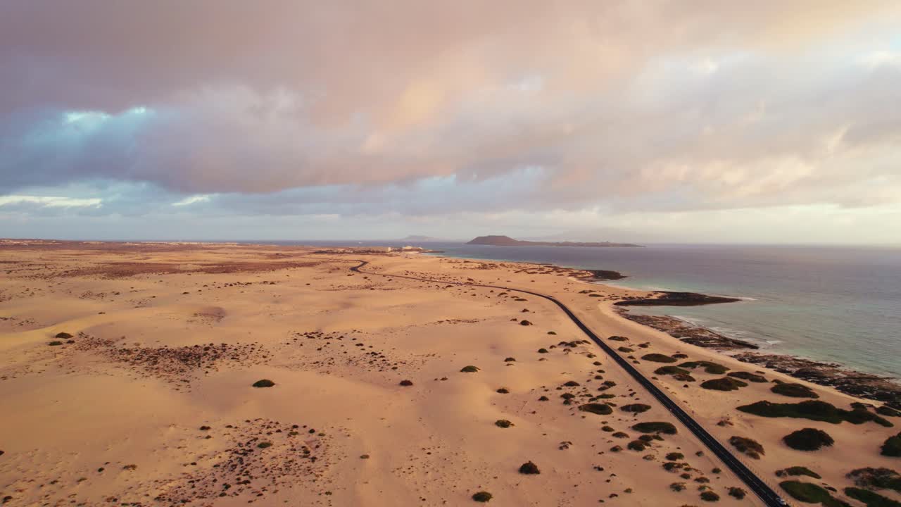 Golden light over dunes, and ocean captures peaceful island beauty and sunrise atmosphere. Aerial 4K drone video of Corralejo at sunrise in Fuerteventura.