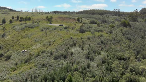 toma aérea de un automóvil estacionado en un mirador de montaña con los restos de un automóvil en la ladera de la montaña