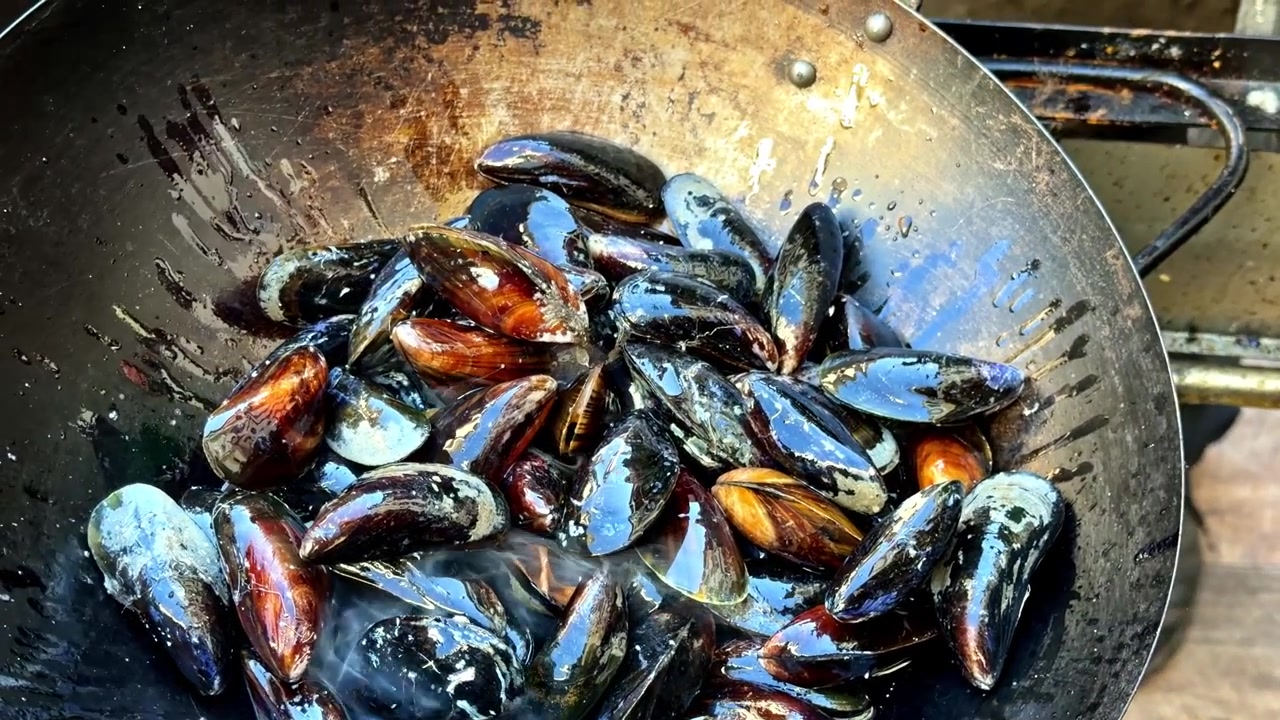 Un lote de mejillones frescos se está cocinando en una sartén - Primer plano.