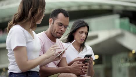 Group-of-young-people-using-devices-on-street