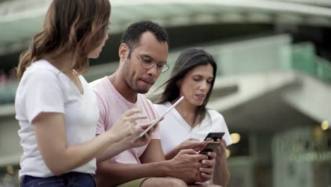 grupo de jóvenes que usan dispositivos en la calle