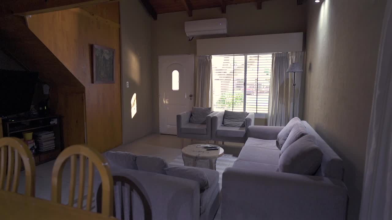 General right slider clip presenting cozy house dining and living room with shades of grey and brown, and shining window in background. Shot on 4K.