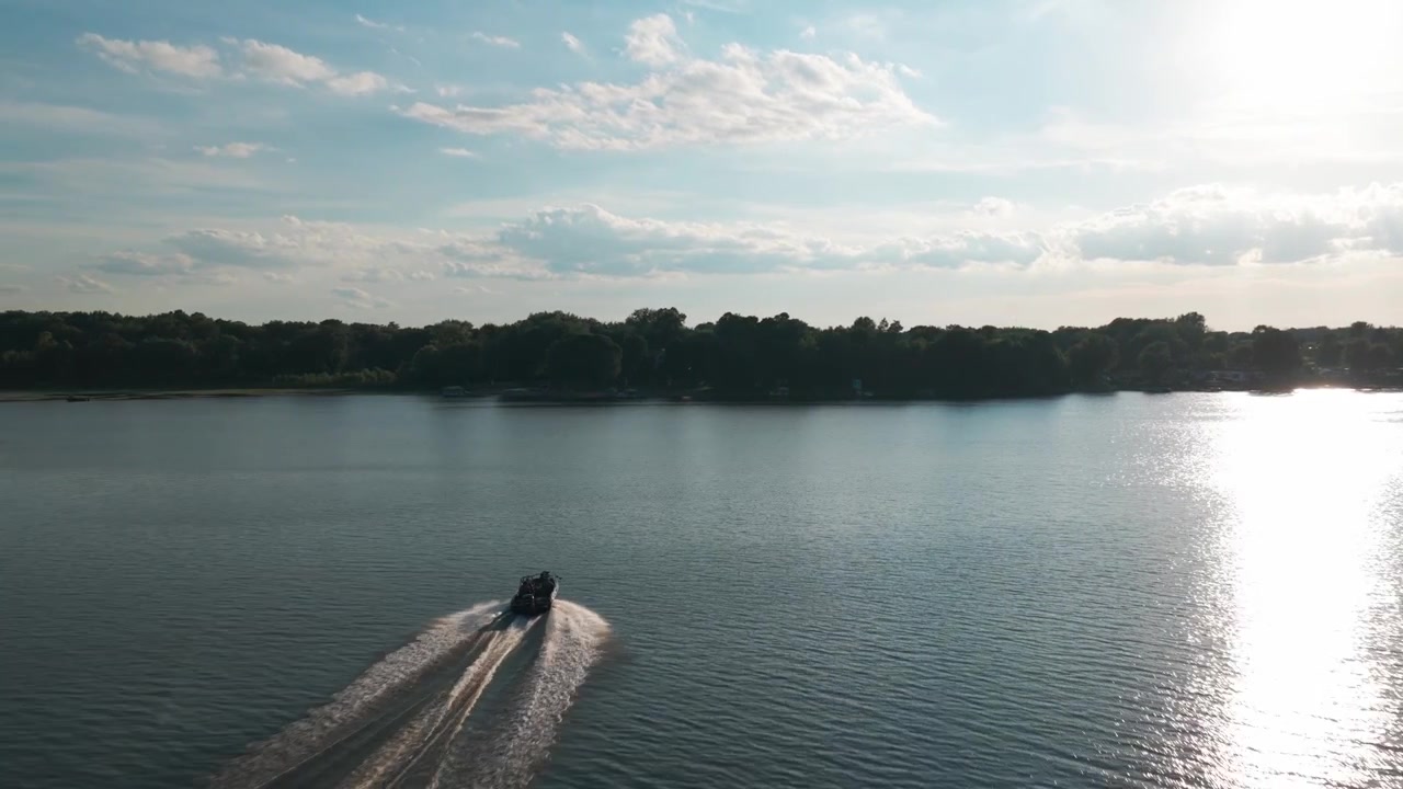 Wide aerial shot following behind a speed boat on a lake in Center City, Minnesota. 4K