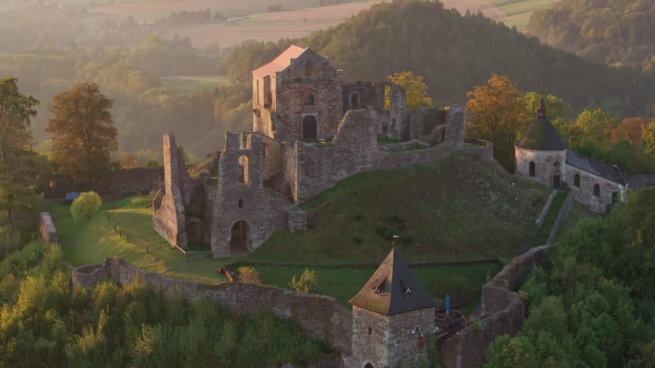 Capture par drone du Château de Potštejn au lever du soleil derrière les collines.