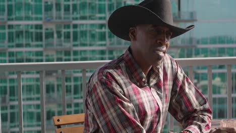 disparo panorámico de un hombre negro con sombrero de vaquero con expresión facial