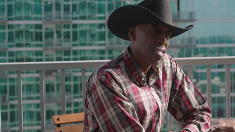 panning shot of black man wearing cowboy hat with facial expression