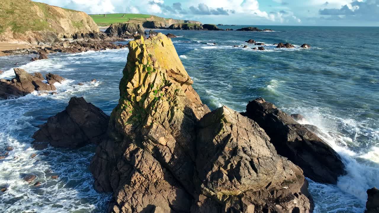 Ireland Epic Locations waves crashing on sea stack with dramatic coastline in background
