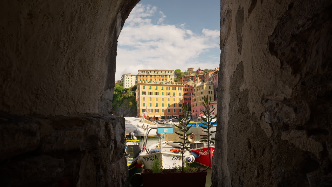 Barche, vista sul porto della città storica attraverso un arco in pietra nel villaggio costiero di Camogli, Italia