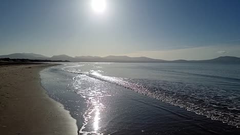 Hazy-Snowdonia-mountain-range-across-idyllic-slow-motion-shimmering-Irish-Seascape-from-Newborough-shoreline