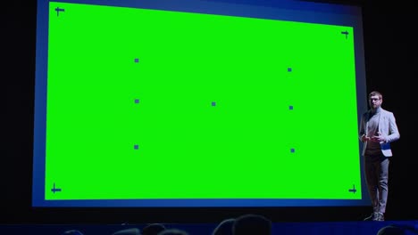 business conference stage: keynote speaker presents new product to the audience, movie theater shows green screen, mock-up, chroma key. live event on health, science and technology