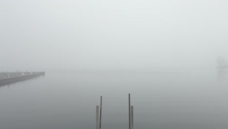 a boat launch dock on a misty lake, reverse motion track revealing it