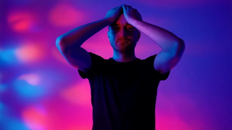 Man Covering Face with Hands in Blue Light
