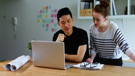 Business-executives-discussing-over-laptop