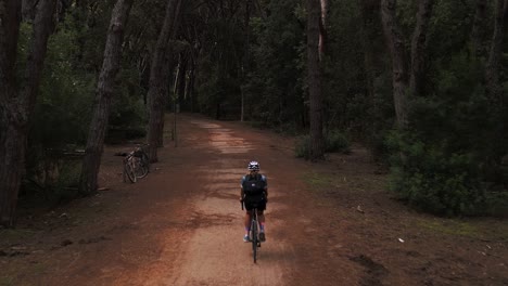 A-young-sporty-woman-cycling-with-a-racing-bike-in-a-pine-tree-forest