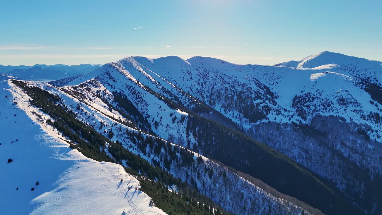 Aerial drone view of the Mala Fatra mountains with snow-covered peaks and hikers along the ridge under clear blue skies, highlighting the pristine beauty of this range. Location: Mala Fatra, Slovakia