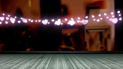 Glowing-pink-heart-shaped-fairy-light-decoration-hanging-over-wooden-plank