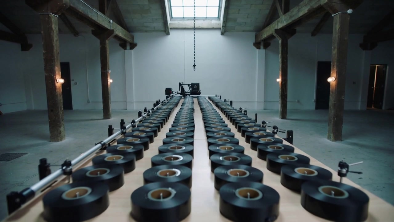 Pushing camera dolly moving forward in loft, revealing black tape rows with rig under skylight