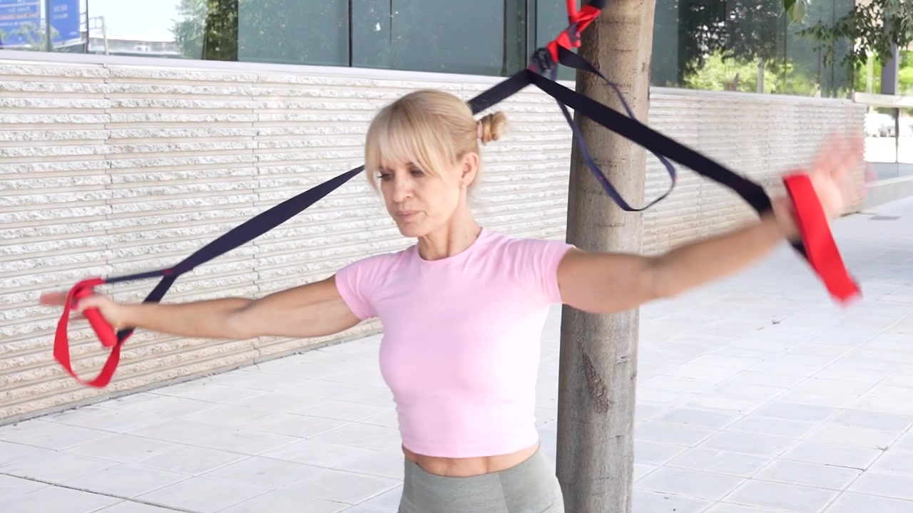 Una donna si allena con fasce di resistenza all'aperto, dando priorità alla sua salute e forma fisica.